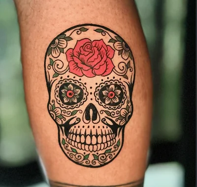 Medium custom tattoo featuring a traditional sugar skull with a red rose and vibrant floral shading.