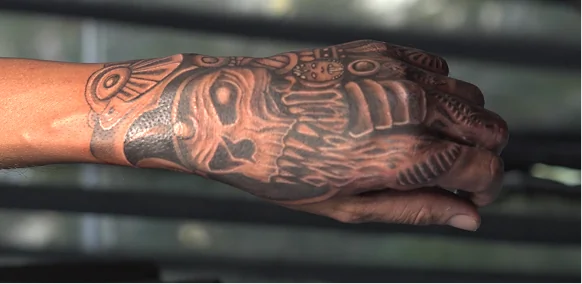 Completed, highly detailed black and grey custom tattoo covering the top of a hand and wrist, featuring deep blackwork shading and intricate patterns.