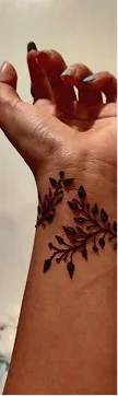 Custom elegant vine henna tattoo design on wrist by professional temporary body art artists.