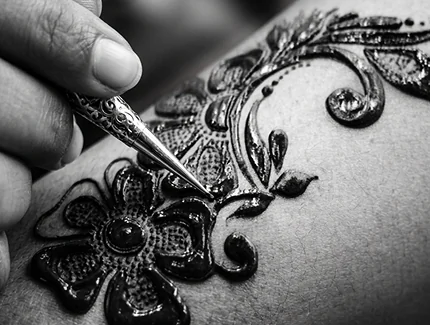 Professional artist applying a detailed floral temporary henna tattoo using natural paste.