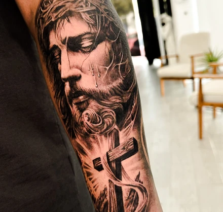 Highly detailed black and grey portrait tattoo of Jesus Christ with a crown of thorns, showcasing expert shading and realism.