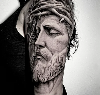 Large blackwork portrait tattoo of Jesus Christ wearing a crown of thorns, featuring highly detailed shading.