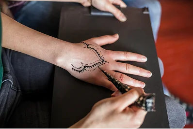 Professional artist applying a long-lasting temporary henna tattoo on a hand