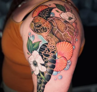 Big custom full-color tattoo featuring a detailed sea turtle swimming among vibrant flowers and coral.